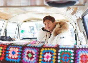 Young man smiling inside a colorful van.