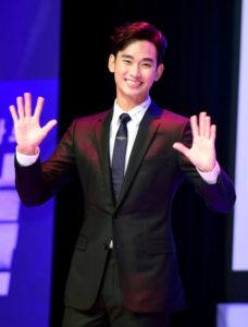 Smiling man in suit waving hands.