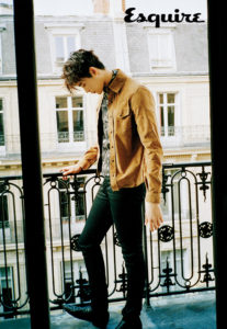 Person standing on balcony in stylish attire.