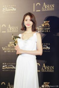 Award recipient in elegant white dress.