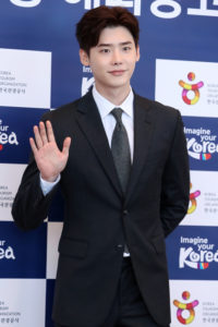 Man in suit waving at an event.