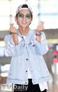 Smiling person showing heart gestures, wearing sunglasses.