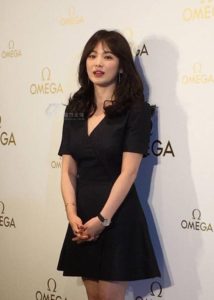 Woman in a short black dress, Omega backdrop.