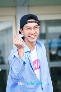 Smiling person gesturing heart with fingers.