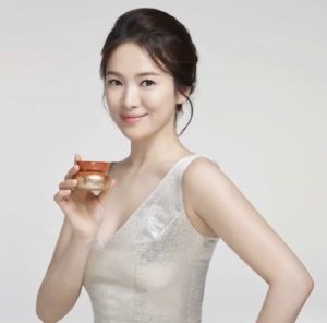 Smiling woman holding skincare product in hand.