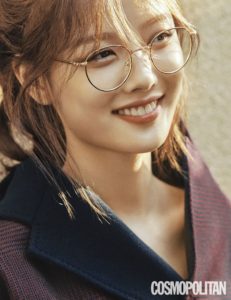 Smiling person wearing glasses and coat.