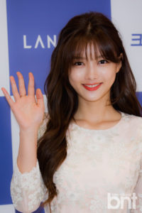 Smiling woman waving at an event.