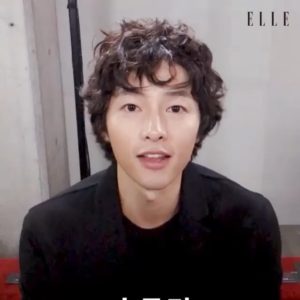 Young man with curly hair smiling.