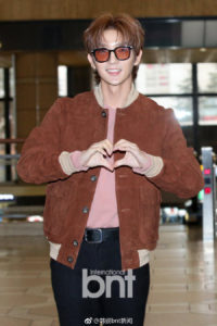 Person making a heart gesture indoors.