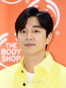 Smiling man in yellow shirt, orange background.