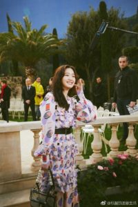 Smiling woman in patterned dress at event.