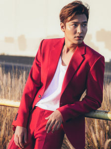 Man in red suit posing outdoors.