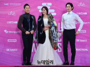 Three people posing on the red carpet.