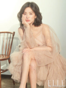 Woman in a stylish, sheer outfit sitting.