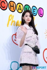 Young woman in stylish pink outfit waving.