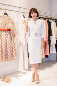 Woman in white dress waves in boutique.