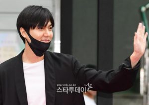 Smiling person waving while wearing a mask.