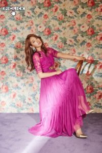Woman in pink dress sitting on chair.