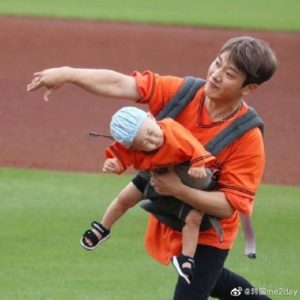 Man wearing an orange shirt with a doll.