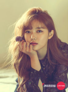 Young woman with long hair holding a flower.