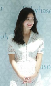 Woman in lace dress smiling softly.