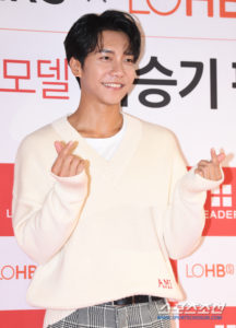 Smiling young man making heart gesture.