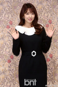 Woman in black dress with white collar.