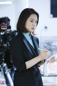 Woman in a suit taking notes on set.
