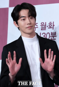 Male celebrity posing with hands raised.