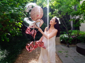 Woman celebrating with balloons in a garden.