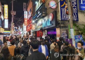 Crowded street with neon signs at night.