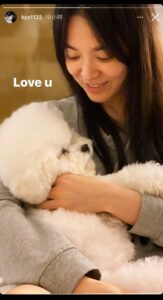 Woman cuddling a fluffy white dog.