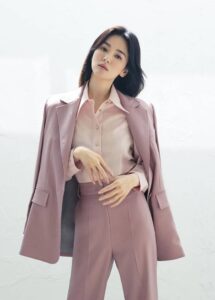 Woman in pink suit, elegant pose.
