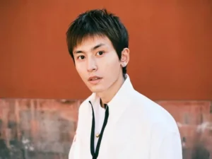 Young man in white shirt against orange background.