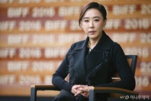 Woman seated, looking directly at camera.