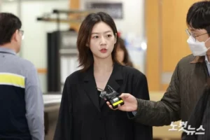 Woman speaking with a reporter in indoor setting.