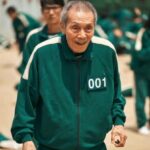 Elderly man in green tracksuit smiling.