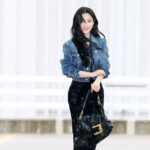 Woman in denim jacket holding a handbag.