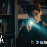 Man holding flashlight in dark library.