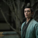 Man in traditional attire, serious expression.