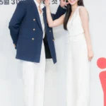 Two people smiling in matching white outfits.