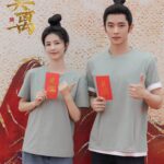 Two people holding red envelopes, smiling.