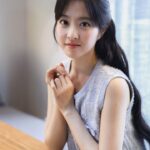 Woman sitting at table, looking at camera.