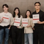 Four people holding scripts, standing together.