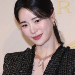 Woman in black jacket smiling at event.