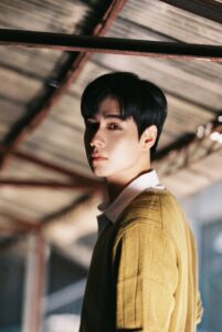Person standing under a rustic roof structure.