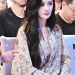 Woman in floral outfit sitting, attentive gaze.