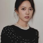 Woman in black dress with pearl necklace.