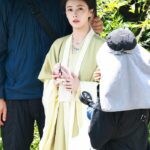 Actress in traditional attire under umbrella.