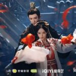 Period drama couple with flowing red ribbons.